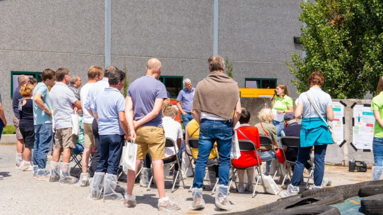 Luisterend publiek bij spreekbeurt op melkveebedrijf in open lucht