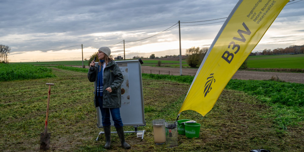 Dame met micro op veld bij b3w vlag en plakkaat