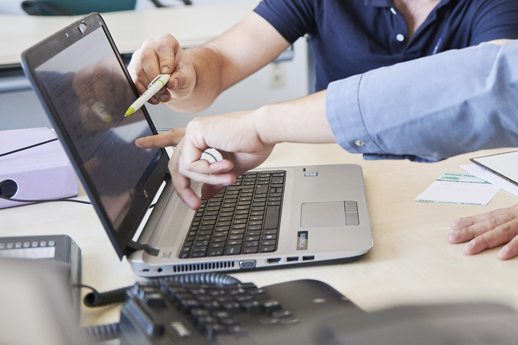 Landbouwer en adviseur bekijken cijfers op laptop
