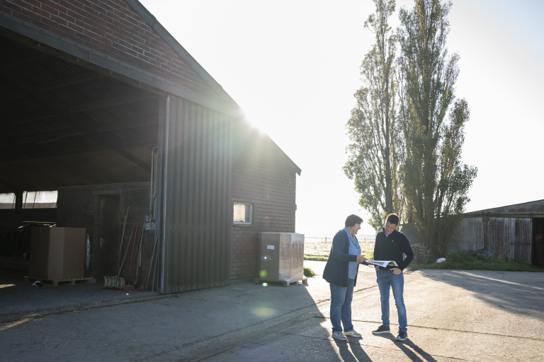 Kathleen geeft advies aan landbouwer Simon buiten de stal.